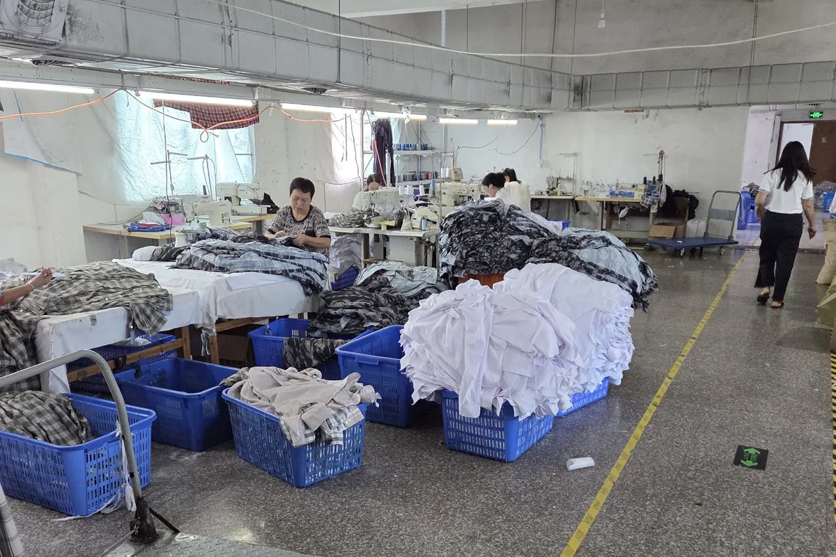 Bundled panels in bins beside sewing machines on a working production floor in China