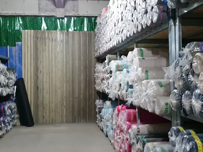 Racks of wrapped fabric rolls in a materials warehouse